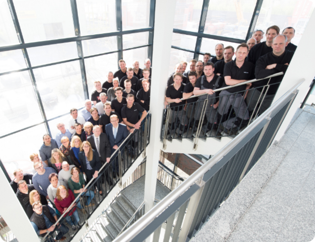 Das gesamte Team der Indunorm Bewegungstechnik im Flur des Firmengebäudes.