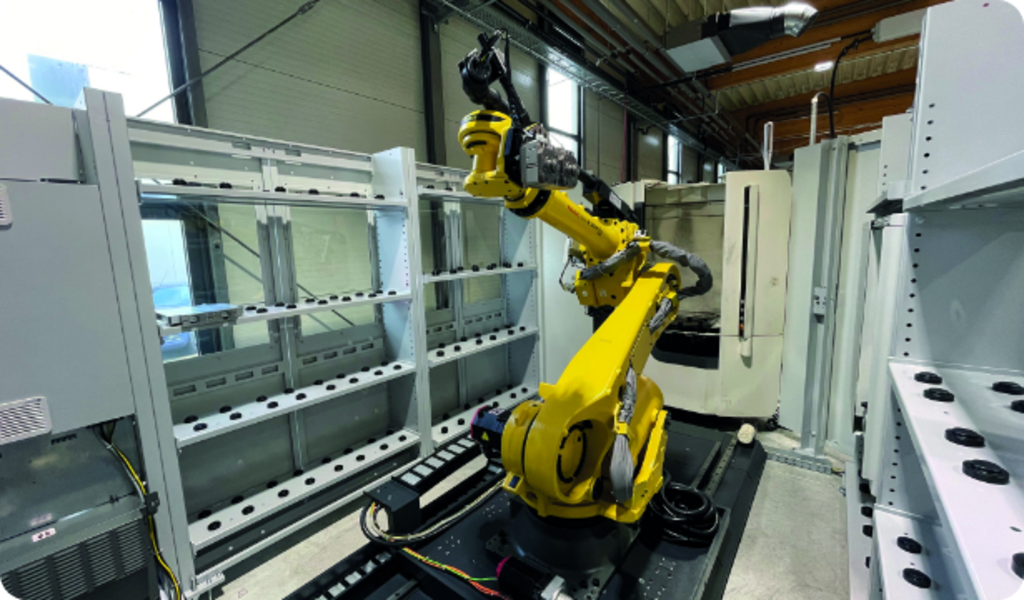 Indunorm installierte eine Indumatik Roboterzelle, die eine vertikale DMU 60 eVo und eine horizontale NHX 4000 zu einer vollautomatisierten Fertigungszelle verbindet.  Mit einem Fanuc R-2000i Knickarmroboter, erweitert durch das Bodenfahrwerk BFW 800 als siebte Achse, konnten alle sieben Achsen zentral gesteuert und überwacht werden.  Die Lösung erlaubte die Verwendung von Paletten unterschiedlicher Größen und das Nachrüsten von Automatiktüren sowie Medienanbindungen, um die Maschinen mit den notwendigen Automationsschnittstellen auszustatten.