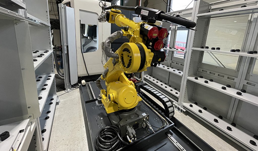 Indunorm installierte eine Indumatik Roboterzelle, die eine vertikale DMU 60 eVo und eine horizontale NHX 4000 zu einer vollautomatisierten Fertigungszelle verbindet.  Mit einem Fanuc R-2000i Knickarmroboter, erweitert durch das Bodenfahrwerk BFW 800 als siebte Achse, konnten alle sieben Achsen zentral gesteuert und überwacht werden.  Die Lösung erlaubte die Verwendung von Paletten unterschiedlicher Größen und das Nachrüsten von Automatiktüren sowie Medienanbindungen, um die Maschinen mit den notwendigen Automationsschnittstellen auszustatten.